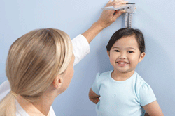 Clinician Measuring the Height of a Smiling Little Girl