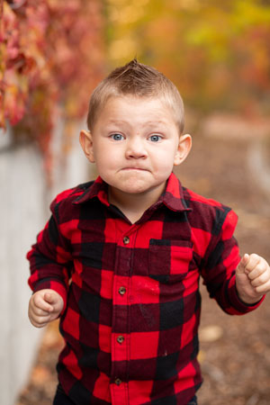 Young boy with Angelman Syndrome looking defiant wearing red plaid shirt